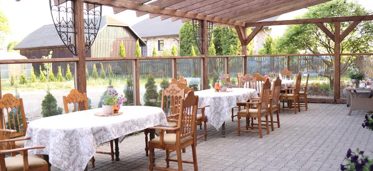 Rustic outdoor terrace with wooden chairs and elegant tablecloths ready for dining.