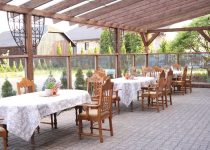 Rustic outdoor terrace with wooden chairs and elegant tablecloths ready for dining.